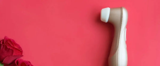 Fondo rojo con una rosa en la esquina inferior izquierda y un Satisfyer Pro 2 en la parte de enmedio